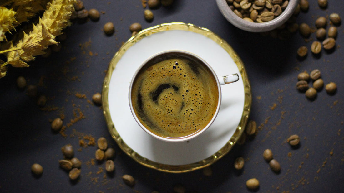 A cup of black coffee on a wooden table beside a notebook