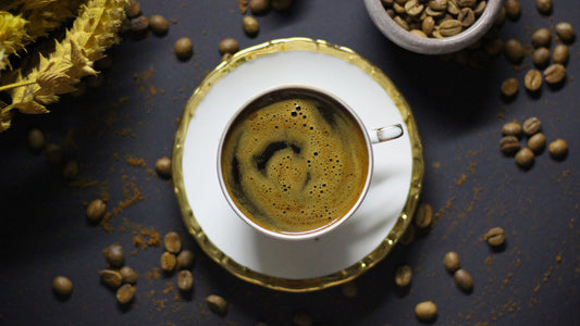 A cup of black coffee on a wooden table beside a notebook