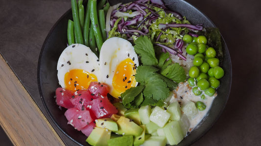 Bowl of grains, vegetables, and grilled protein on a wooden table