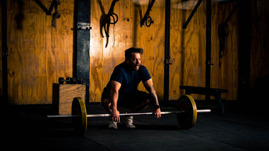 Lifter gripping a loaded barbell on a gym floor