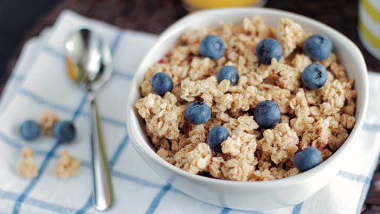Bowls of whole grains, seeds, and fresh produce arranged on a wooden table