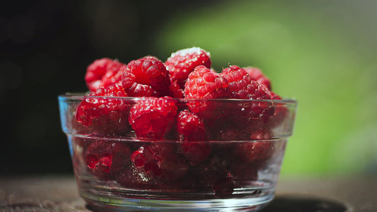 Fresh red raspberries in a white bowl on a wooden table