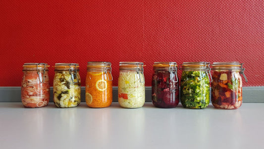 Glass jars of fermented vegetables and yogurt on a wooden kitchen counter