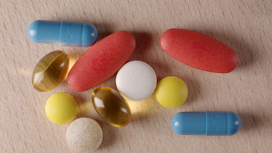 Supplement capsules arranged on a light wooden surface next to a glass of water