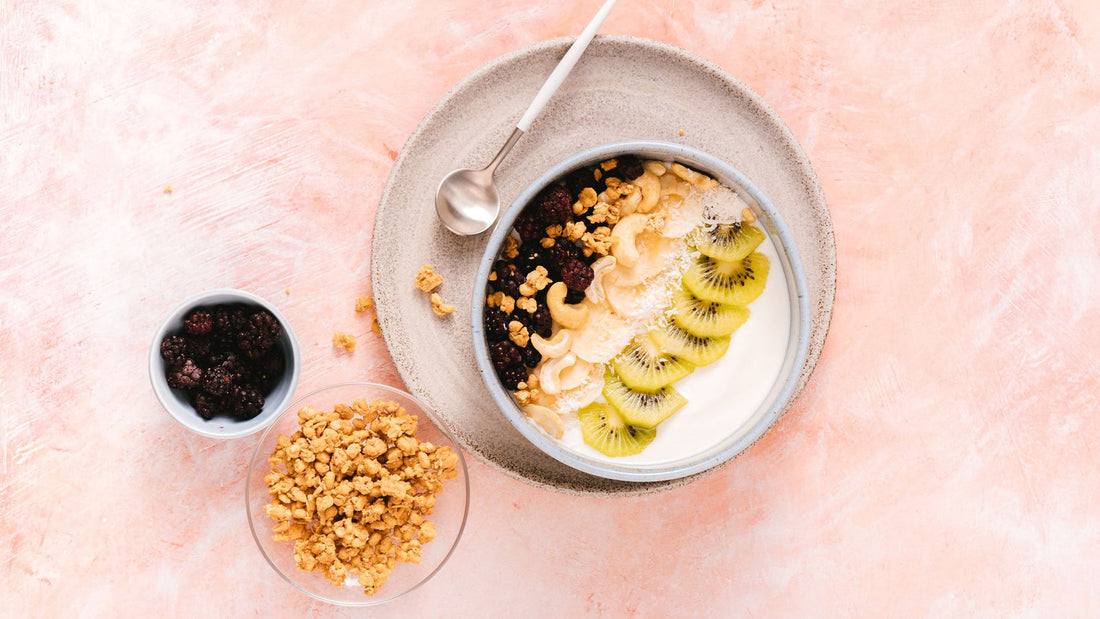 Bowl of plain yogurt topped with berries and seeds on a wooden table