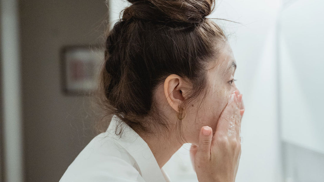 Person rinsing their face with water at a sink
